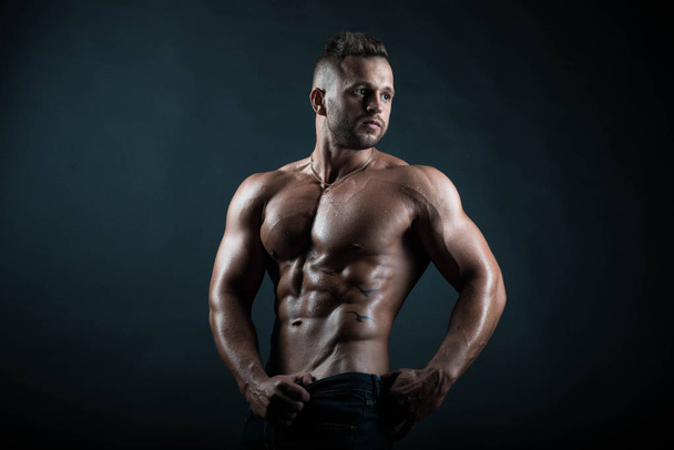 Young handsome, strong male fitness model /  bodybuilder poses on isolated background showing his perfect abs - Zdjęcie, obraz
