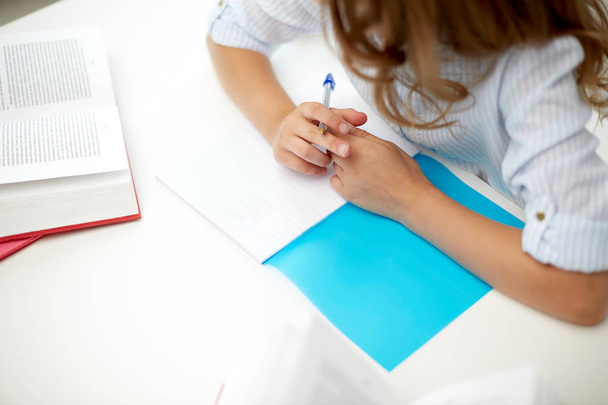 girl with book writing to notebook at school - Photo, Image