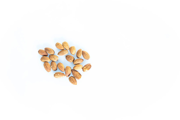 Delicacies almonds scattered on the white background  - Zdjęcie, obraz