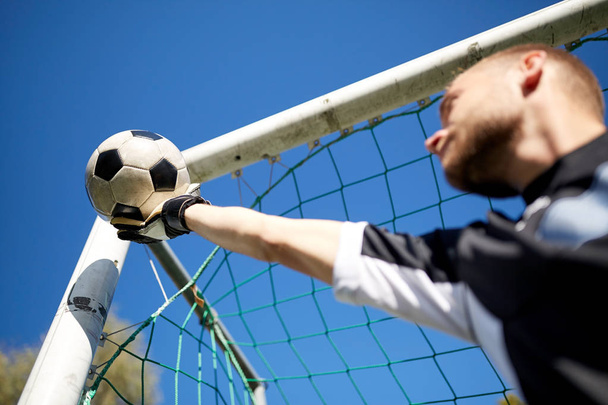 goalkeeper with ball at football goal on field - Foto, afbeelding