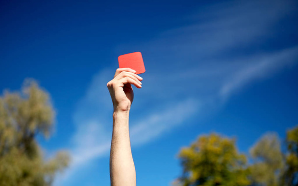referee hands with red card on football field - Foto, afbeelding