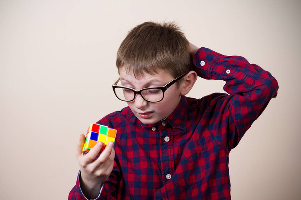 Confident smiling little boy nerd ,holding a puzzle cube .Concept - Foto, afbeelding