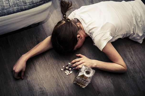 drunk or poisoned young woman with bottle of alcohol and pills - Foto, Imagem