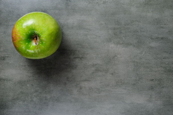 one green apple on dark stone background, top view. - Photo, Image