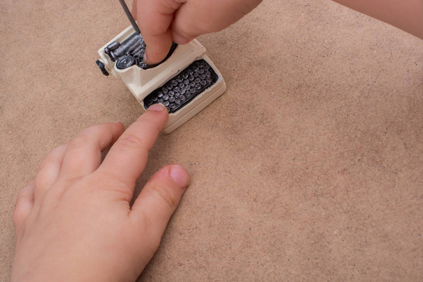 Рука тримає ретро-складану крихітну модель друкарської машинки
  - Фото, зображення