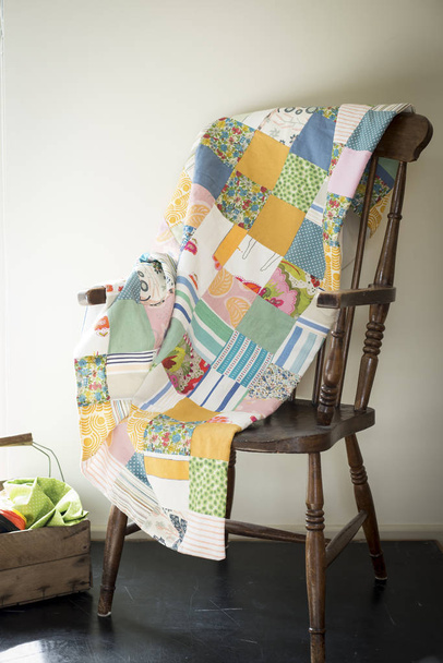 Cobertor de retalhos multicolorido em uma cadeira de madeira antiga
 - Foto, Imagem