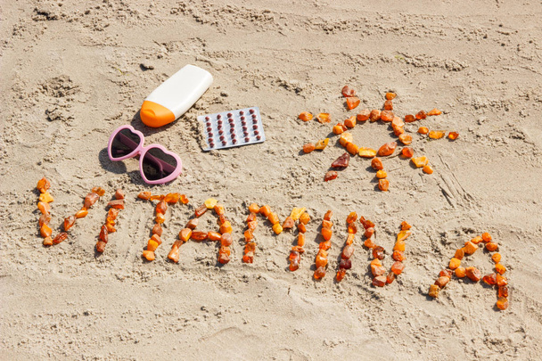 Medical pills, inscription vitamin A and accessories for sunbathing on sand at beach, healthy, beautiful and lasting tan - 写真・画像