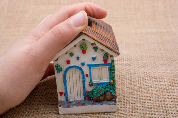 Mano y una pequeña casa modelo
  - Foto, Imagen