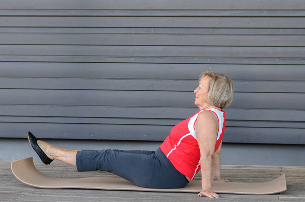 Senior woman doing exercises on a gym mat - Photo, Image