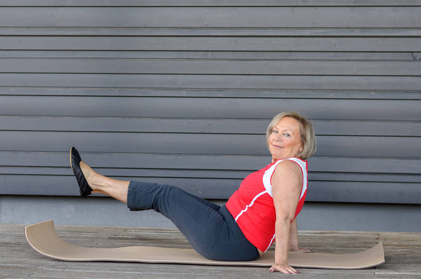 Mujer mayor haciendo ejercicios en una colchoneta de gimnasio
 - Foto, Imagen
