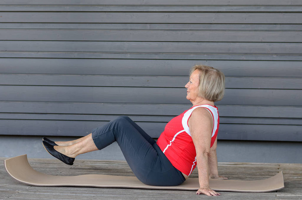 Mujer mayor haciendo ejercicios en una colchoneta de gimnasio
 - Foto, imagen