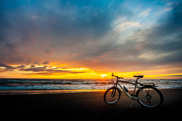Toeristische fiets aan de kust van de zee bij zonsondergang tijd - Foto, afbeelding