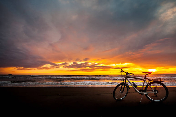 Τουριστική ποδήλατο στην ακτή της θάλασσας κατά το ηλιοβασίλεμα - Φωτογραφία, εικόνα