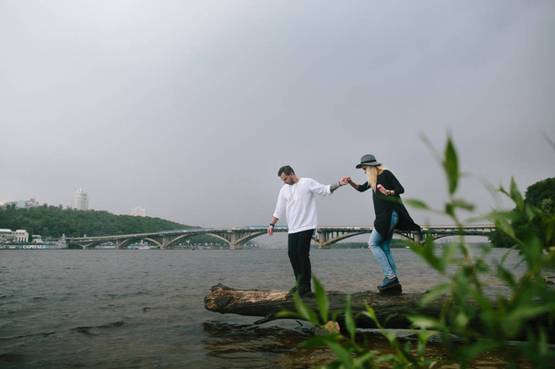  Beautiful stylish couple in love walking near river. - Фото, изображение