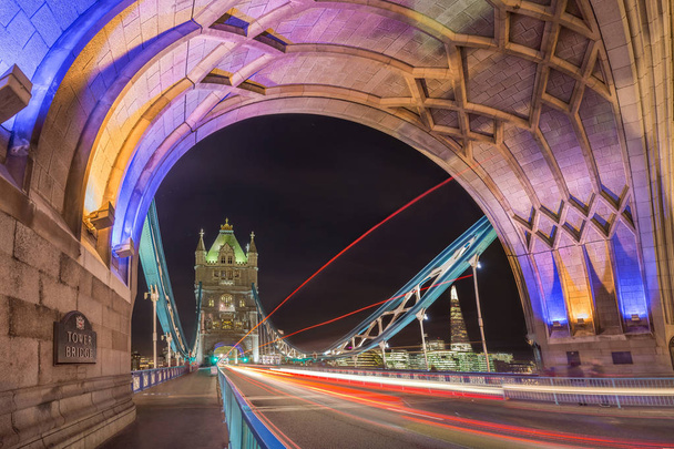 Λονδίνο, Αγγλία - Night shot του κόσμου διάσημο πολύχρωμο Tower Bridge στο Λονδίνο με διπλό λεωφορείο decker φως μονοπάτια και γραφεία και θραύσμα ουρανοξύστη στο παρασκήνιο - Φωτογραφία, εικόνα