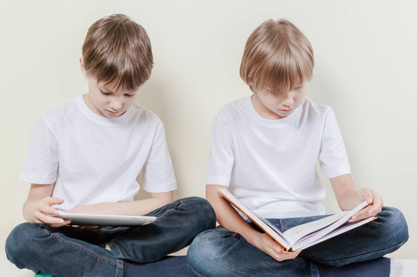 Junge mit Tablet-Computer und Kind beim Lesen eines Buches. Bildungsfreizeitkonzept für Kinder. - Foto, Bild
