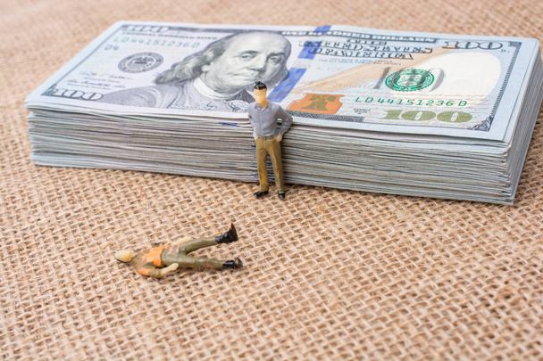 Men figurines beside the bundle of US dollar banknote  - Photo, Image