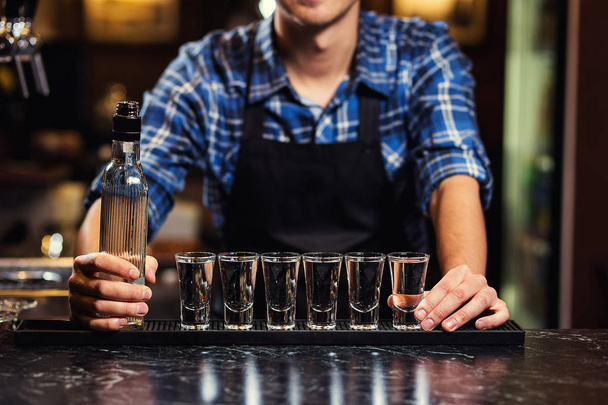Barman v práci, Barman lití tvrdé ducha do sklenic v detailu, barman se nalil tequila do skla, příprava koktejlů, pojem o službě a nápoje - Fotografie, Obrázek