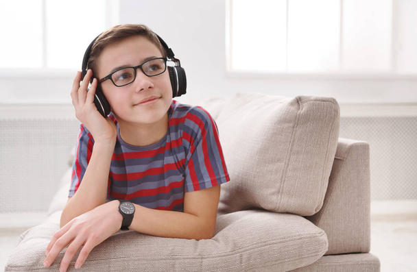 10 代の少年が自宅でヘッドフォンで音楽を楽しむ - 写真・画像