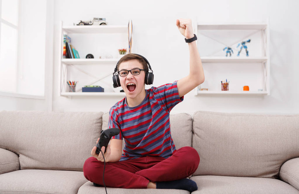 Захоплений хлопчик-підліток грає у відеогру вдома
 - Фото, зображення