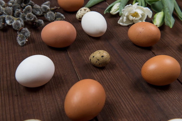 Huevos de Pascua y flores sobre una mesa marrón
 - Foto, imagen