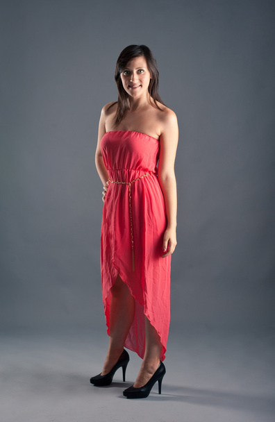 Beautiful woman with red dress against grey background - Zdjęcie, obraz
