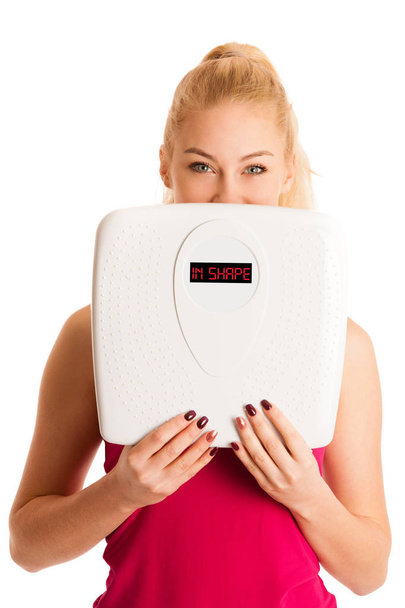 Happy young blond woman showing a scale as she has perfect shape - Foto, afbeelding