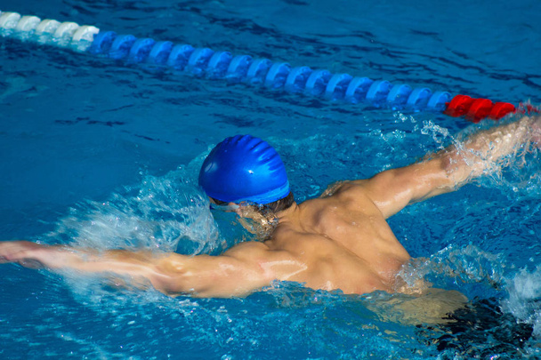 Young man swimming the front crawl in a pool - Foto, afbeelding