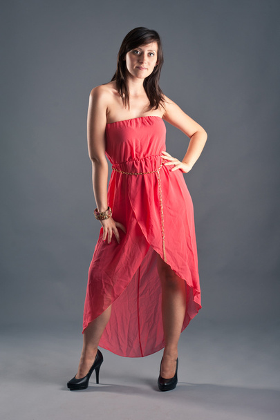 Beautiful woman with red dress against grey background - Zdjęcie, obraz