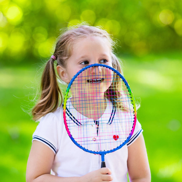 Lapsi pelaa sulkapalloa tai tennistä ulkona kesällä
 - Valokuva, kuva