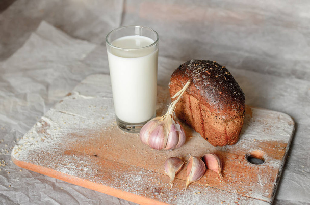 Pour milk into a glass on the background of bread - Valokuva, kuva