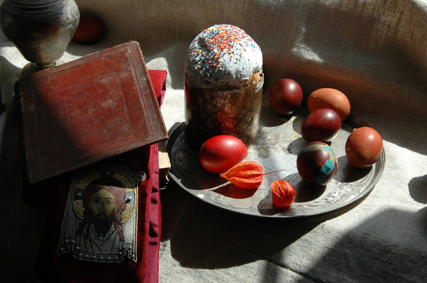 La naturaleza muerta de Pascua con la Santa Biblia, pastel de Pascua y huevos teñidos
 - Foto, Imagen