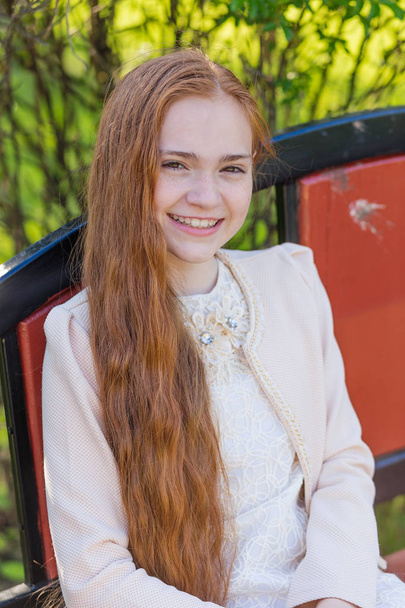 Portrait of a cute girl with long red hair in the park - Foto, afbeelding