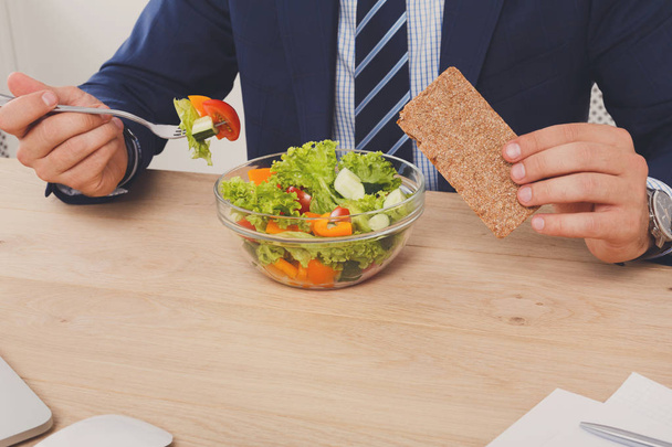 Hombre irreconocible tiene almuerzo de negocios saludable en el interior de la oficina moderna
 - Foto, imagen