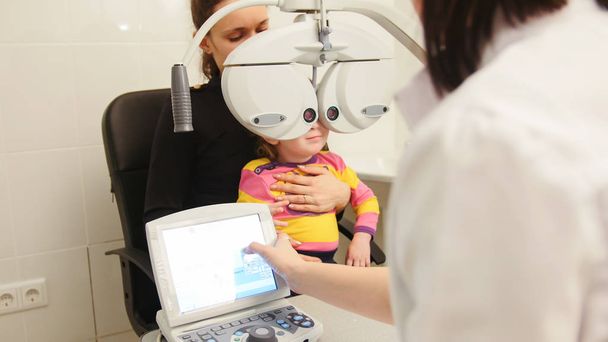Petite fille mignonne avec maman à l'ophtalmologiste sur consultation
 - Photo, image