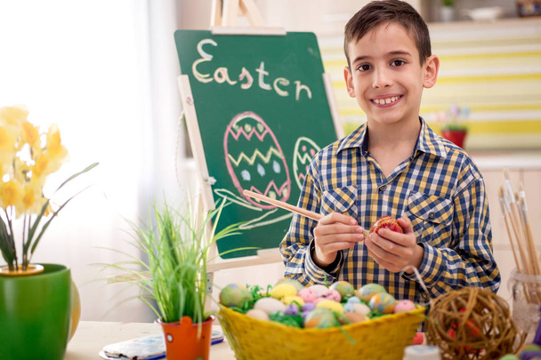smiling boy draws easter eggs - Foto, afbeelding