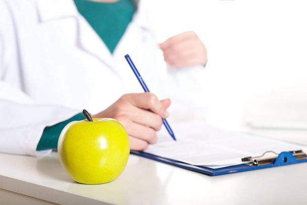 Jeune étudiante médecin assis avec pomme sur un fond blanc
 - Photo, image