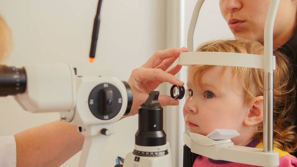 Childs ophthalmology - doctor optometrist checks eyesight at little girl - Photo, Image