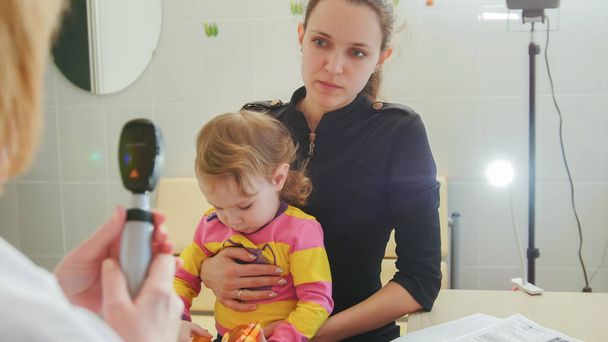 Oogheelkunde-arts geeft overleg aan de moeder van het meisje over het gezichtsvermogen van kleine meisje-Childs Healthcare - Foto, afbeelding