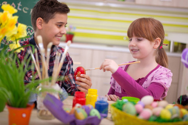 Two smiling kids paint easter eggs - Foto, afbeelding