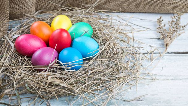 Colorful easter eggs in hay on wooden background - Photo, image