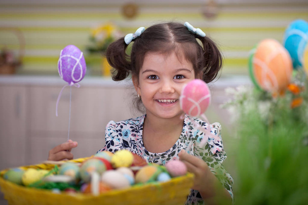 Cute little girl with basket full of colorful easter eggs - Foto, imagen