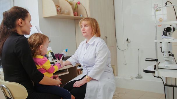 Optometrist checks childs eyesight - mother and child have consultation in ophthalmologist room - Photo, Image