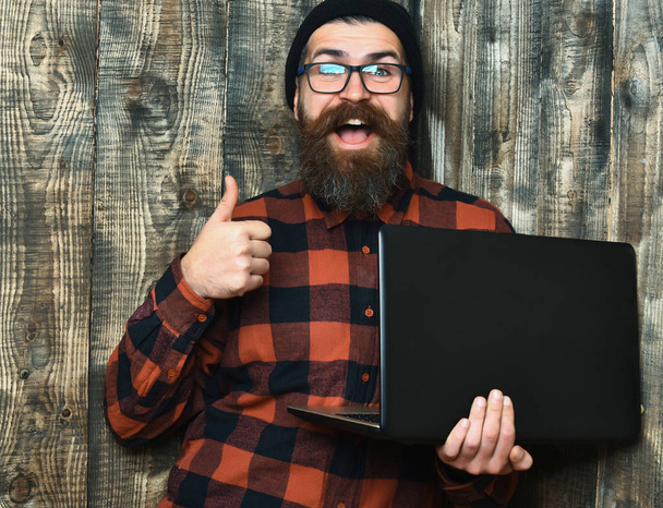 Bearded brutal caucasian hipster holding laptop - Photo, image