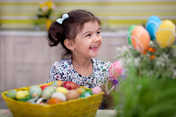Cute little girl with basket full of colorful easter eggs - Fotoğraf, Görsel