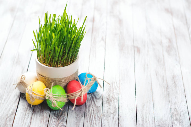 Színes húsvéti tojások, virágcserép, zöld fű, fa háttér. Hely, a szöveg. Szelektív összpontosít. - Fotó, kép