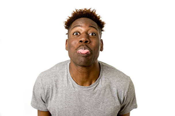 schwarzer afroamerikanischer Mann sieht glücklich und verspielt gestikulierend aus und zeigt lustigen albernen Gesichtsausdruck - Foto, Bild