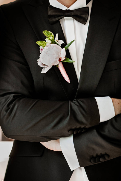 Pink peon boutonniere pinned to a grooms jacket - Photo, image