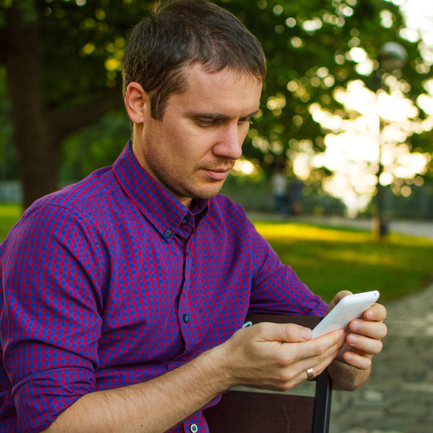 Zachování připojení. Mladý muž psaní zprávy na jeho mobilní telefon. Náměstí - Fotografie, Obrázek