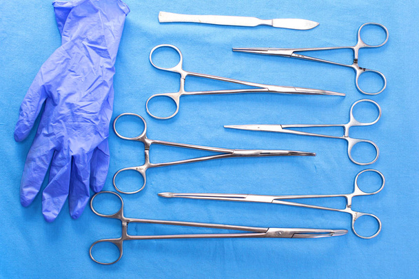Chirurgische Instrumente und Werkzeuge wie Skalpelle, Pinzetten und Pinzetten auf einem Tisch für eine Operation angeordnet - Foto, Bild